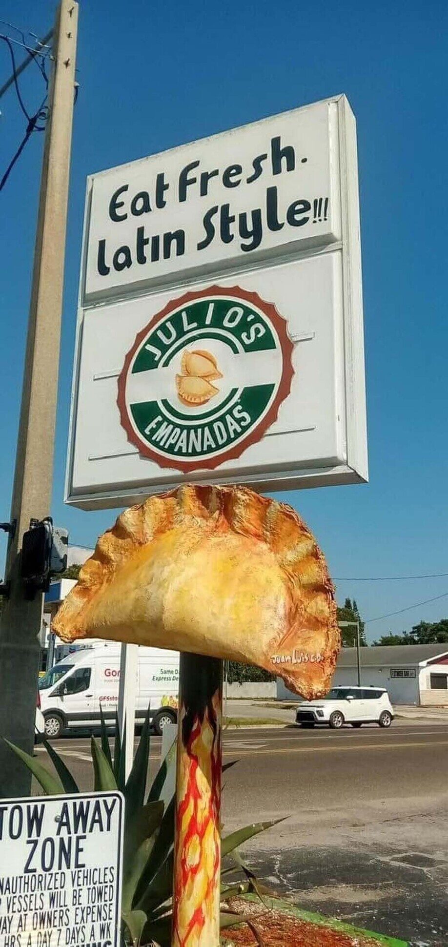 Julio's Empanadas road sign reading 'Eat Fresh. Latin Style!!!' with painted empanada sculpture