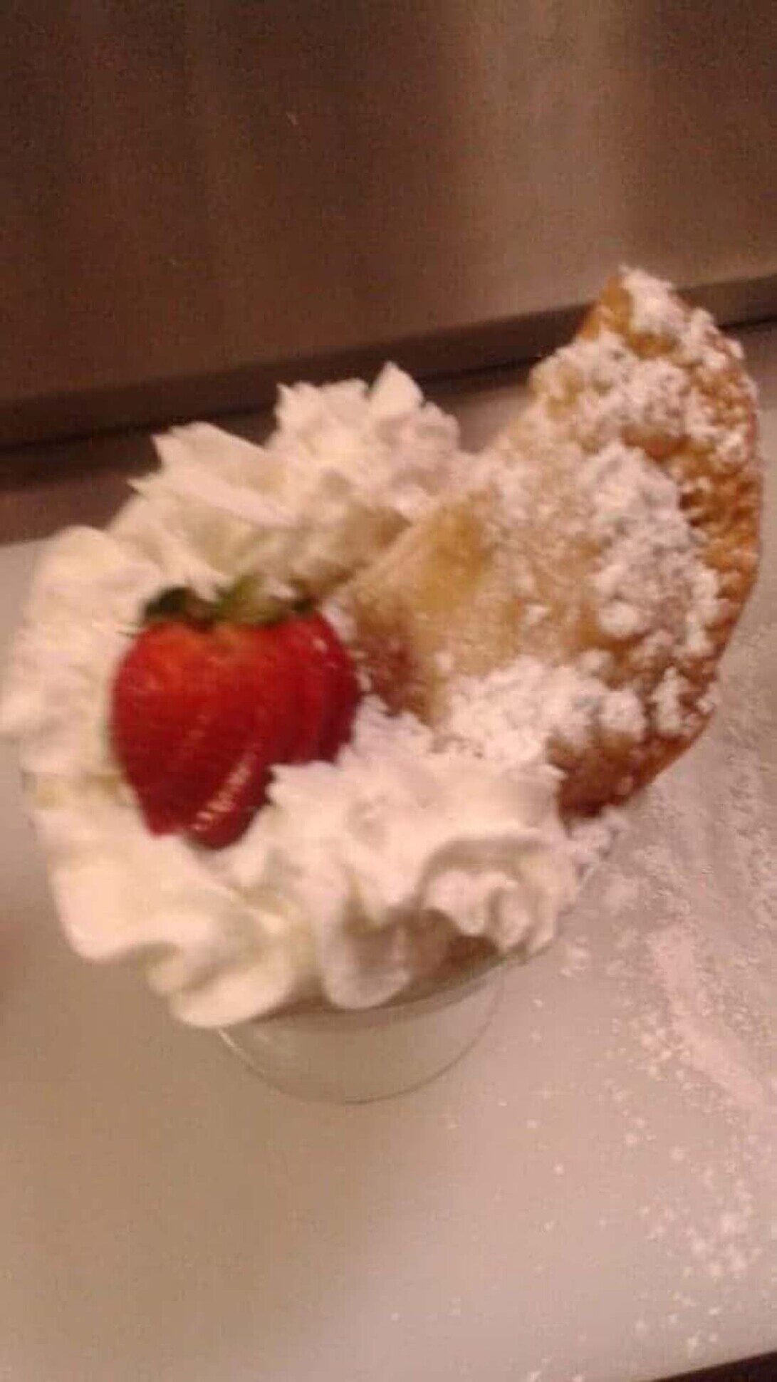 Dessert empanada with powdered sugar, fresh whipped cream, and strawberry
