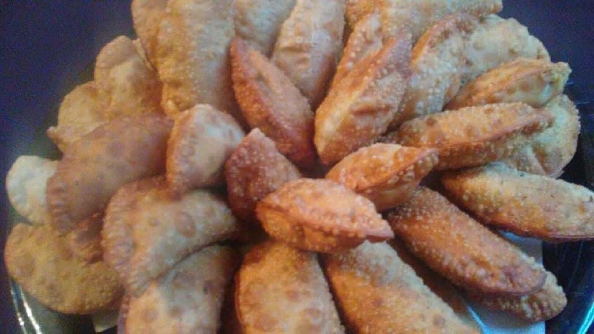 Platter of assorted golden-brown handcrafted empanadas in various sizes and styles